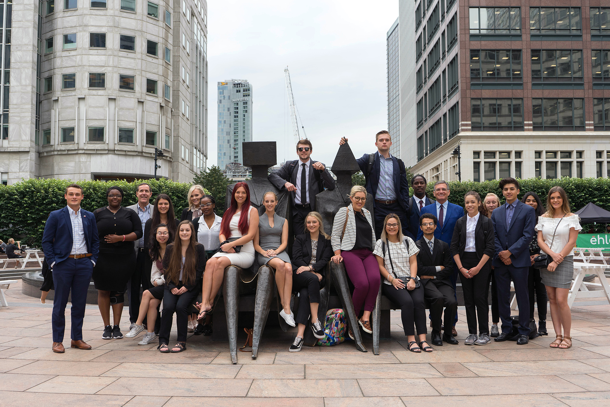 Business students studying abroad, posing in front of a sculpture