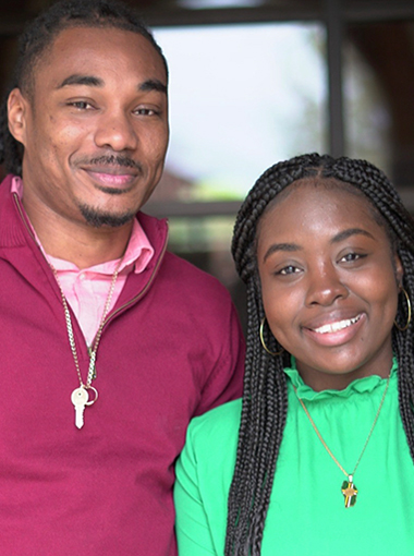 Two students stand together, smiling, outside of Dillard College of Business Administration building.