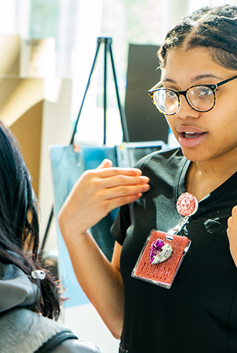 A student converses with another student at an event on campus.