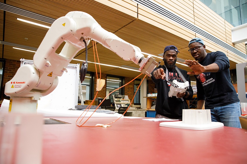 Engineering students with a robotic arm