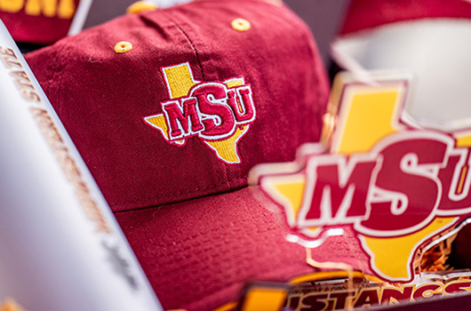 Various MSU Texas branded prizes that were handed out during Maroon March 2024: a sports cup, MSU Texas hat, and desk decor, all in Maroon and Gold.