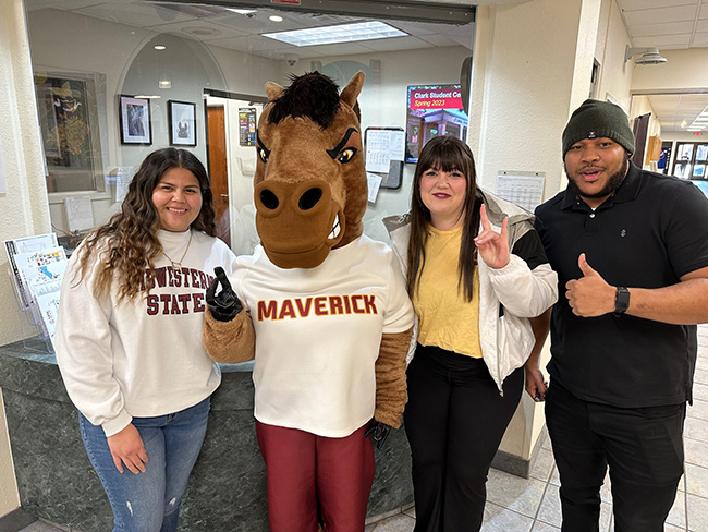 Maverick the Mustang posing with a group of students inside Clark Student Center on March 10, 2023.