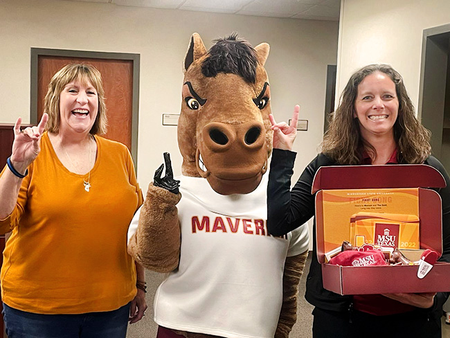 Maverick the Mustang posing with staff holding the MSU Texas spirit box gift, inside the Bruce and Graciela Redwine Student Wellness Center on March 24, 2023.