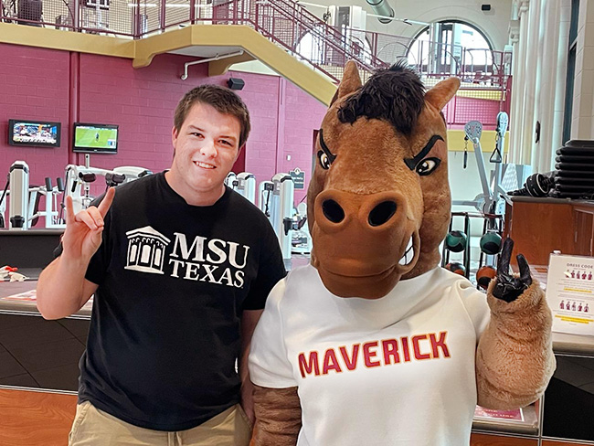 Maverick the Mustang posing with student staff inside the Bruce and Graciela Redwine Student Wellness Center on March 24, 2023.