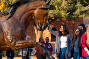 A student standing with a sculpted horse