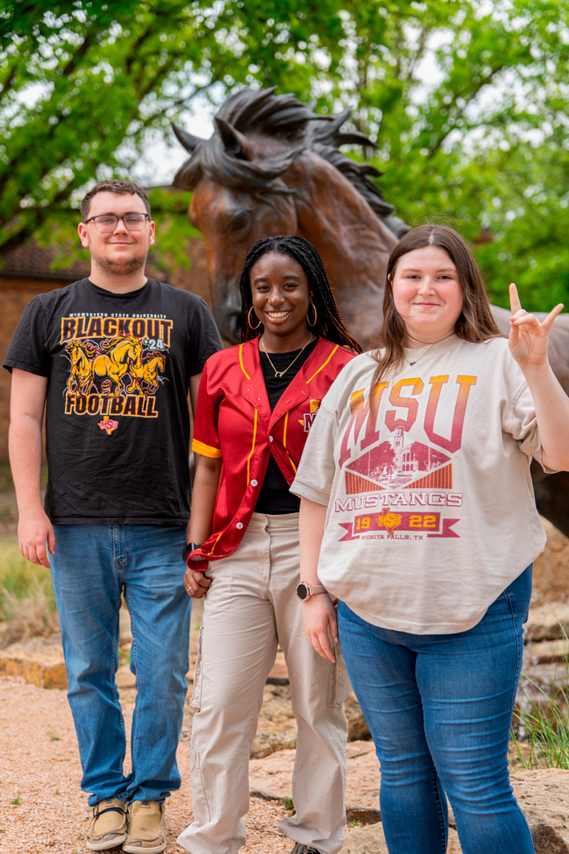 Students standing in front of the mustang statue