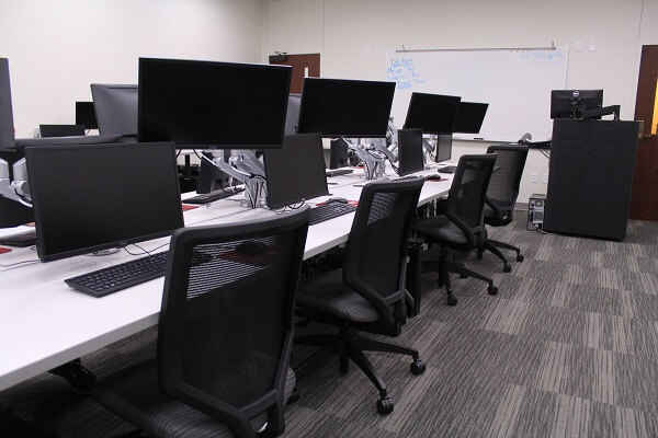 A row of desks inside of the broadcast lab, downstairs in the Mass Communication building.