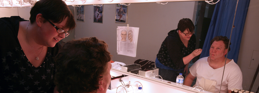 Person applying makeup to an actor's face.