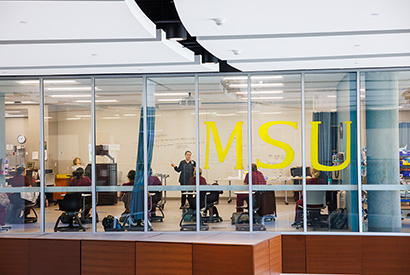 Students learn in class while a professor teaches in Centennial Hall.