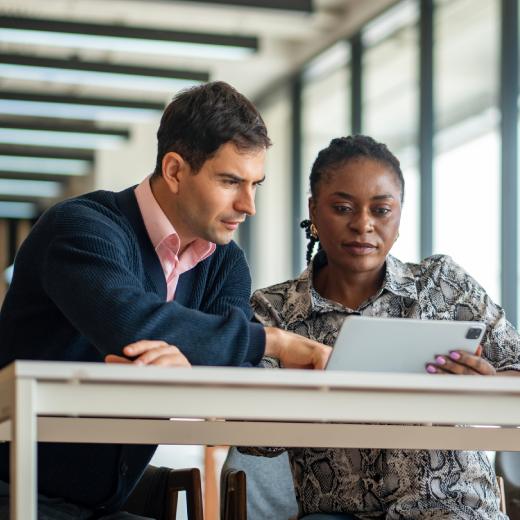 A man and a woman looking at a tablet.