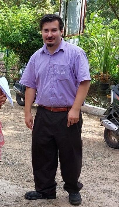 A man standing in front of a motorcycle smiling.