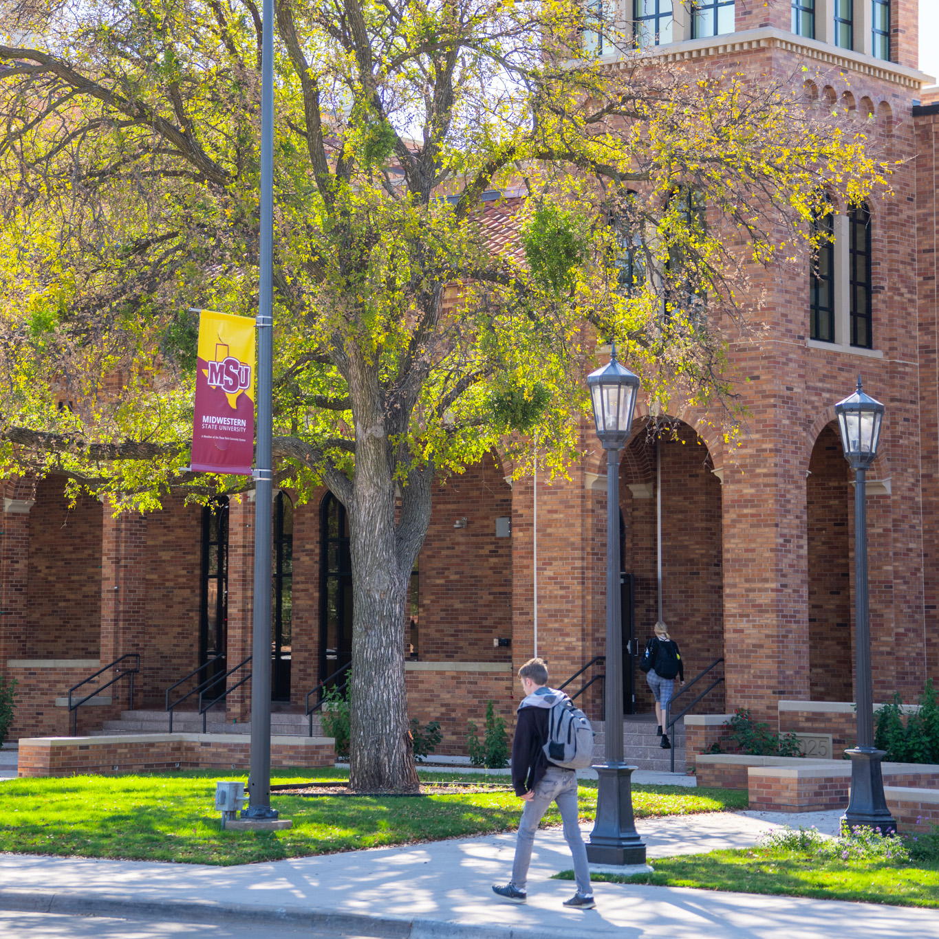 Students walk past Bolin Hall on a bright, sunny day.