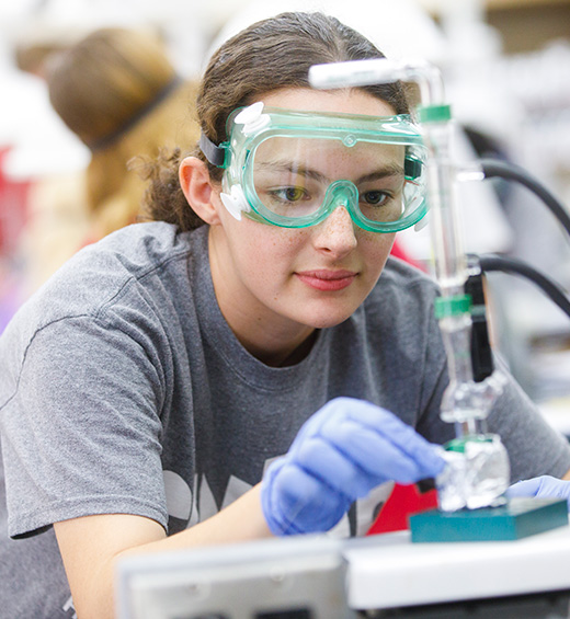 A student wearing safety goggles does work in the lab inside Bolin Science Hall.