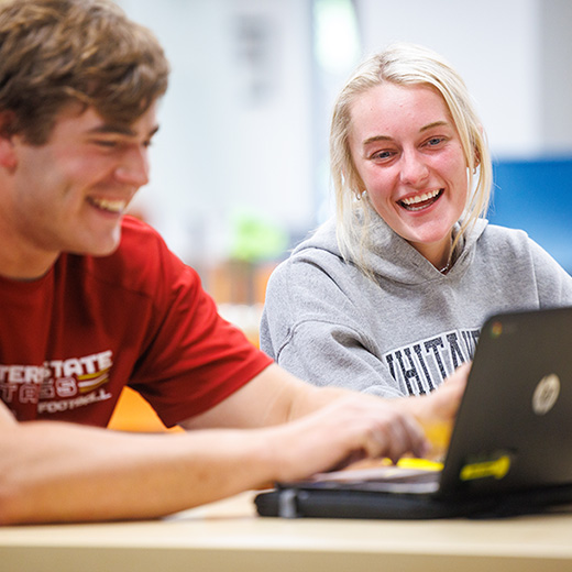 Two students happily work together in the TASP Learning Center, inside Moffett Library.