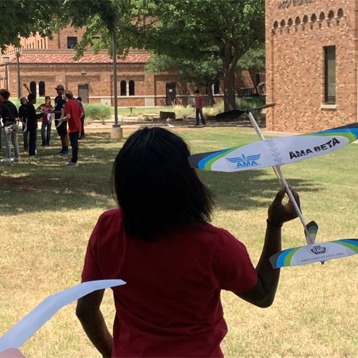 Students playing with the planes they created during their lesson, outside in the quad.