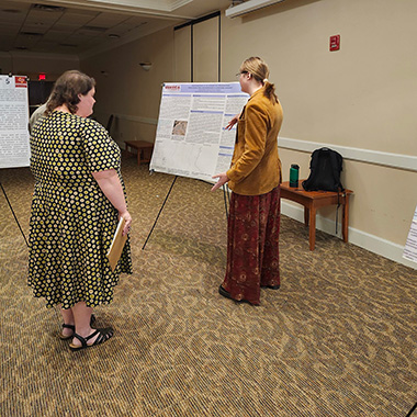 A student presents her research as a professor listens to her presentation during EURECA undergraduate research.
