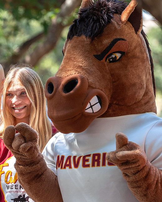 Photo of a smiling MSU Texas student posing with Maverick T. Mustang, the MSU Texas mascot.