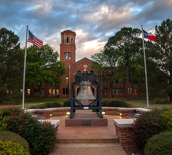 Exterior shot of Hardin Administration Building from Taft Boulevard with the American flag flying on the left side and the Texas flag flying on the right side.