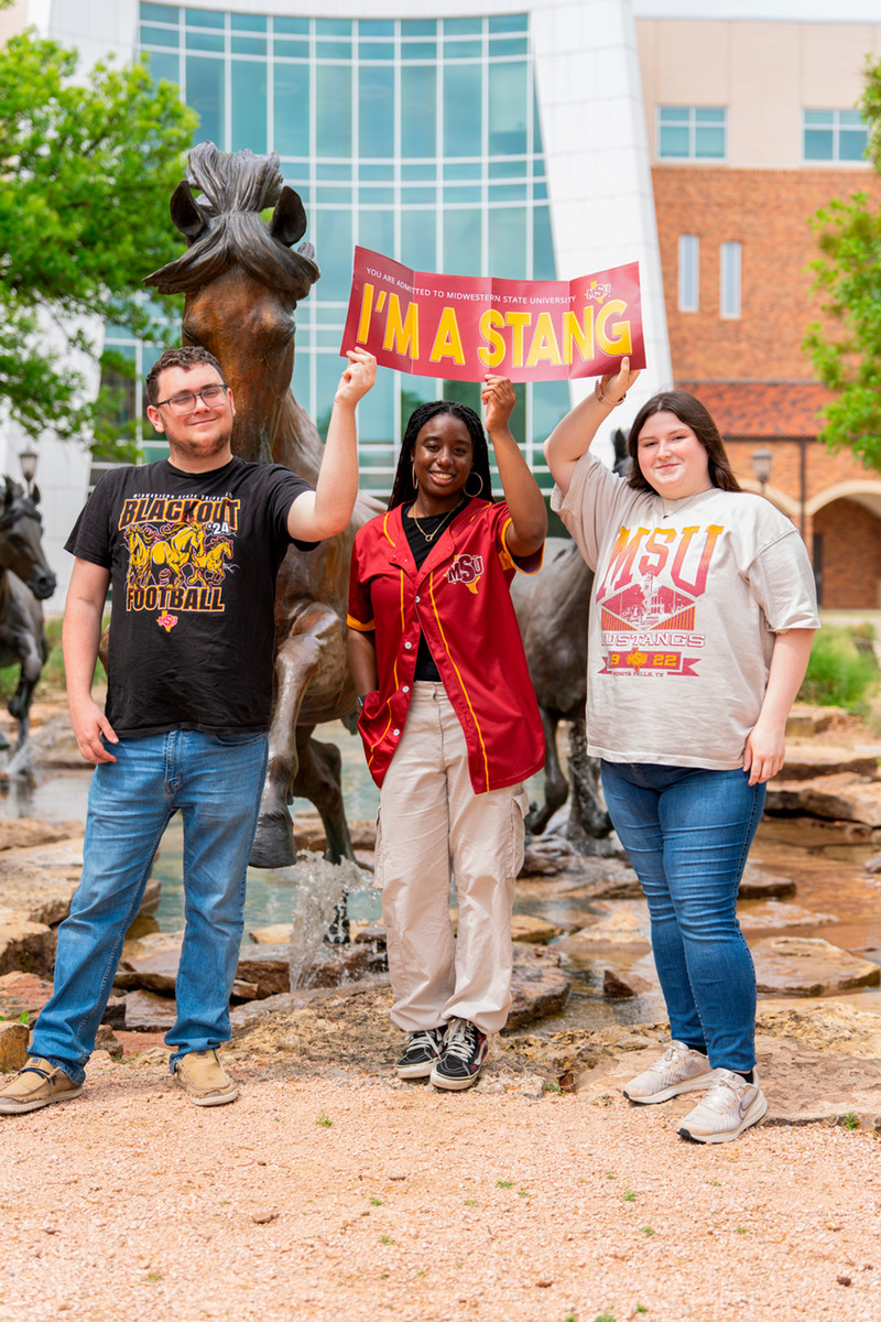 Three MSU students with a stang sign
