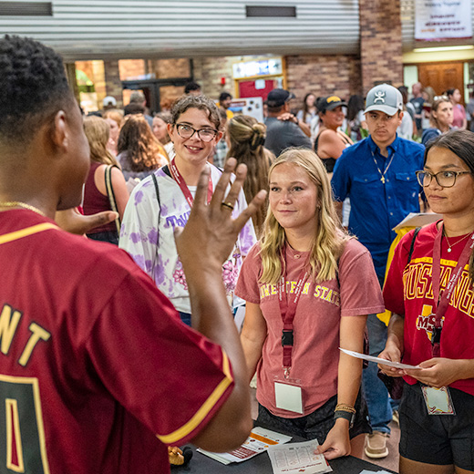 An orientation leader answers questions to a group of students at orientation.