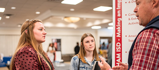 Two students engage with a potential employer at the career fair.