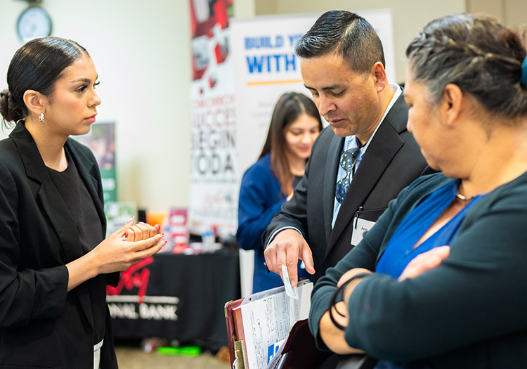 Several students engage in conversation with potential employers at the career fair.