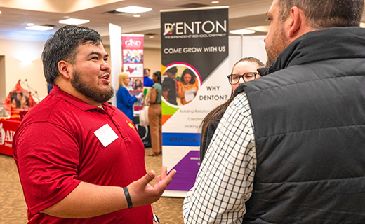 Students converse and engage with a potential employer at a career fair hosted by the MSU Texas Career Management Center.