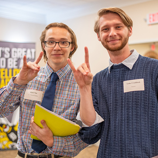 Two MSU Texas students hold up the Mustangs Hand Sign during a Career Fair.