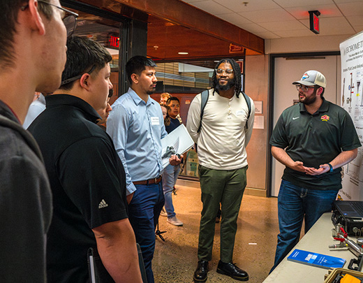 A group of students converse with a potential employer in the McCoy Engineering Hall during the Career Fair hosted by the Career Management Center.