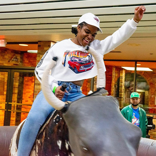 A student happily takes a turn riding the mechanical bull during an event in Clark Student Center.