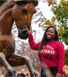 A student touches the nose of one of the mustangs in the Spirit of the Mustangs statue during an event.
