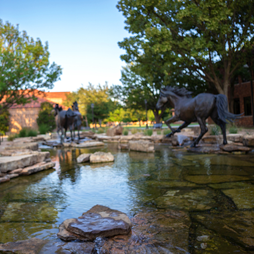A view of the Spirit of the Mustangs statue facing Dillard College of Business Administration.