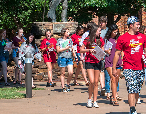 Image of students walking near statue. 