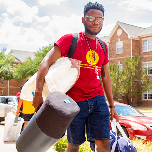 A student helps a new student move in to the residence hall during Move In Day.
