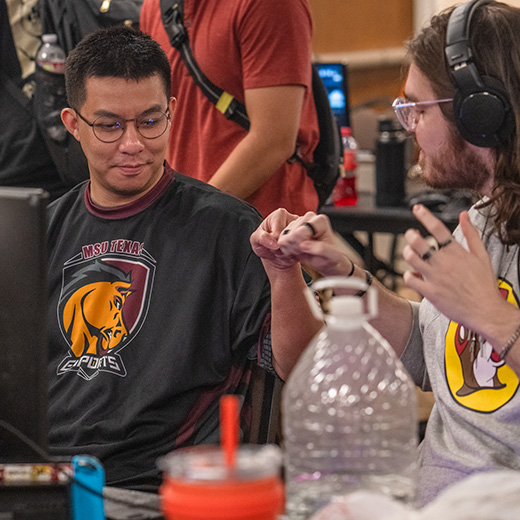 Two Esports players share a fist bump during a moment of teamwork at an Esports event.