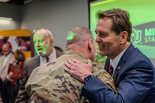 An Airman receives a hug during the Military Education Center grand opening ceremony in Bridwell Activities Center.