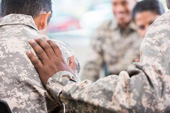 A group of Military members converse and comfort each other during a support group meeting.