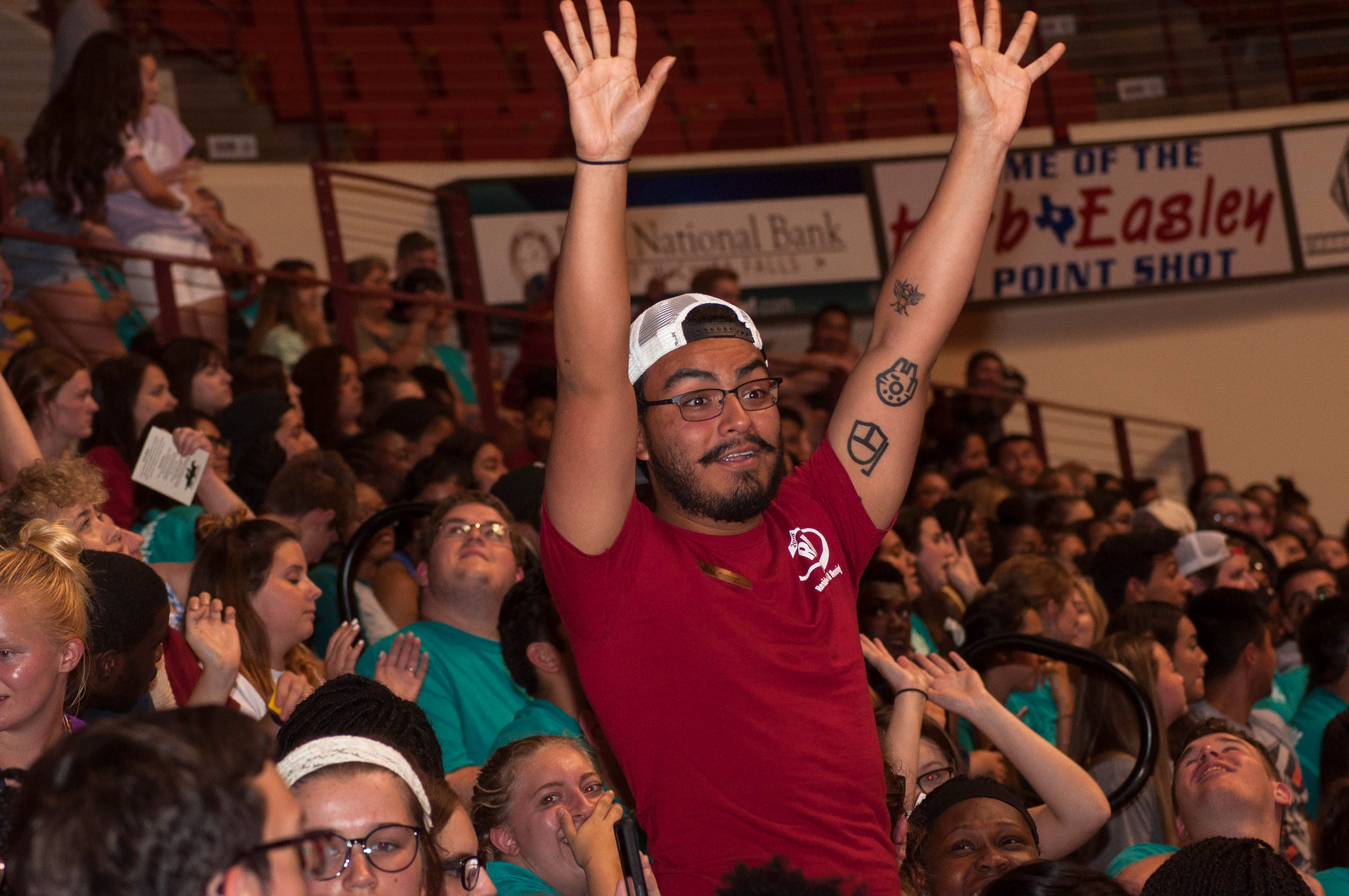 Convocation A student is standing up, arms waving, surrounded by other students during the 2018 Convocation event