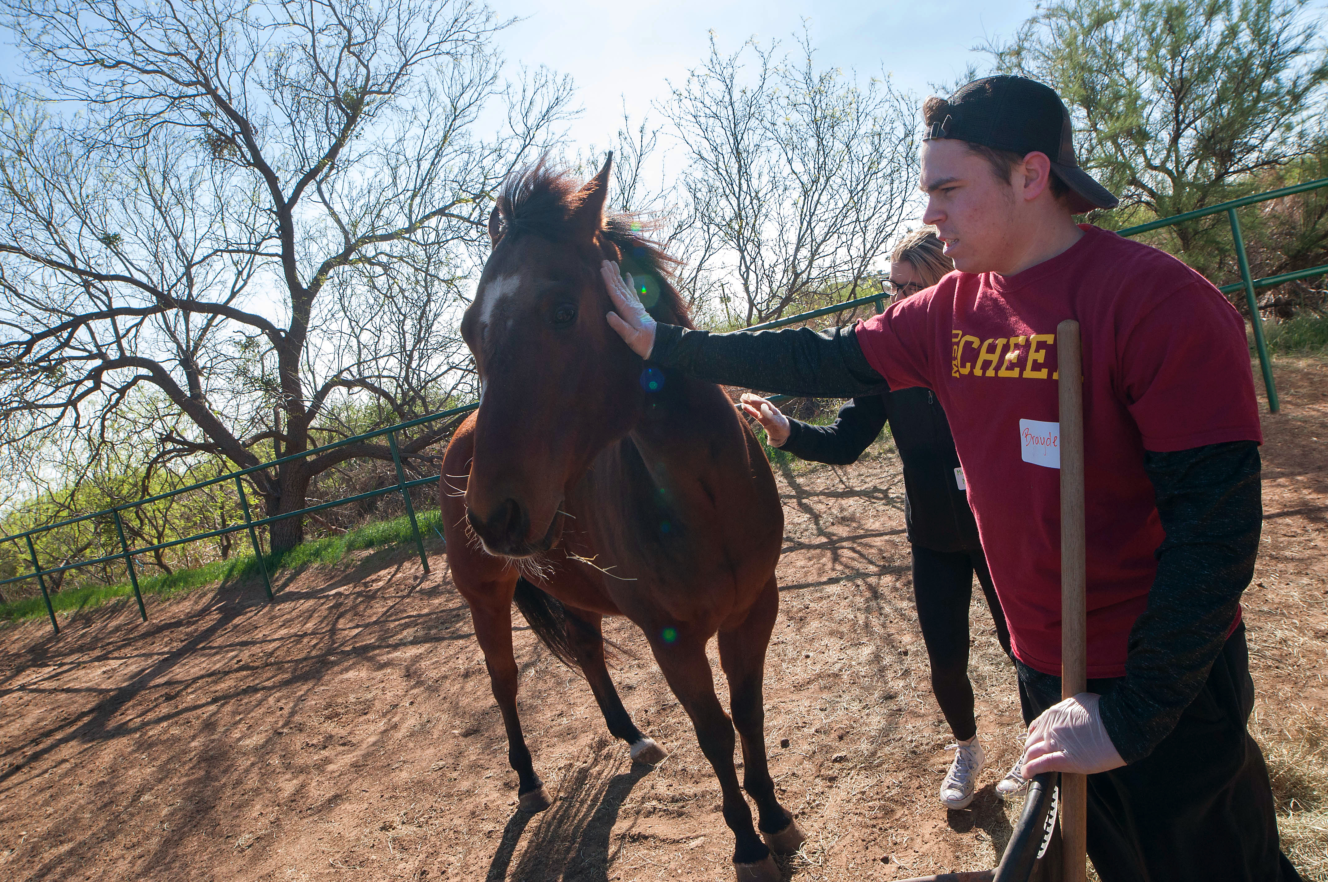 Two students petting a horse after cleaning out the pen at Whispers of Hope
