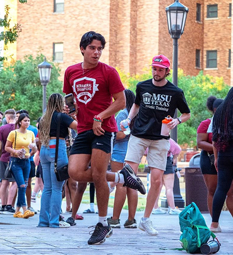 A group of students dance in the Legacy Courtyard during an event.