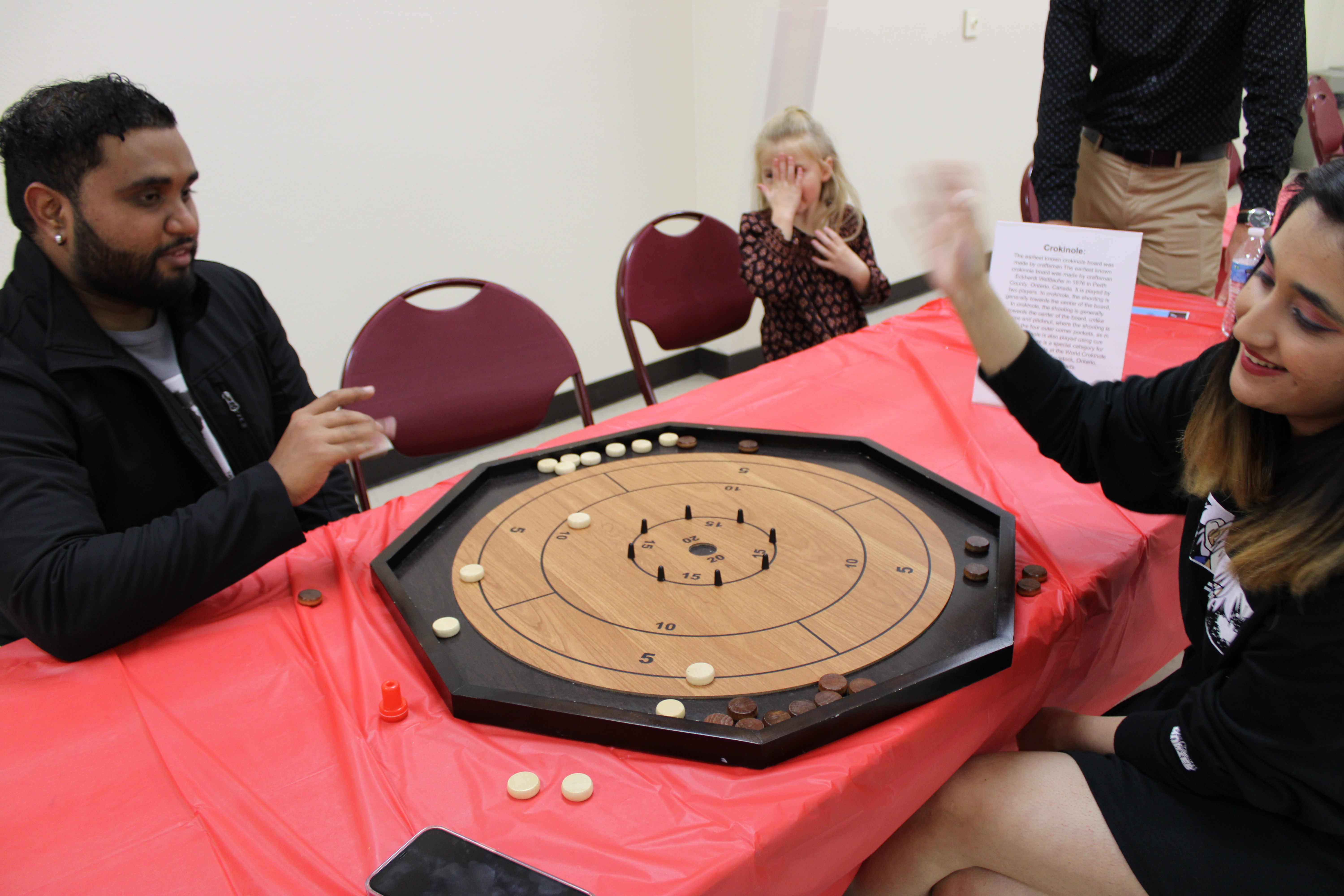 Two students, one male and one female playing Crokinole at International Game Night.