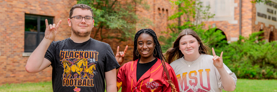 Three MSU students with stangs up
