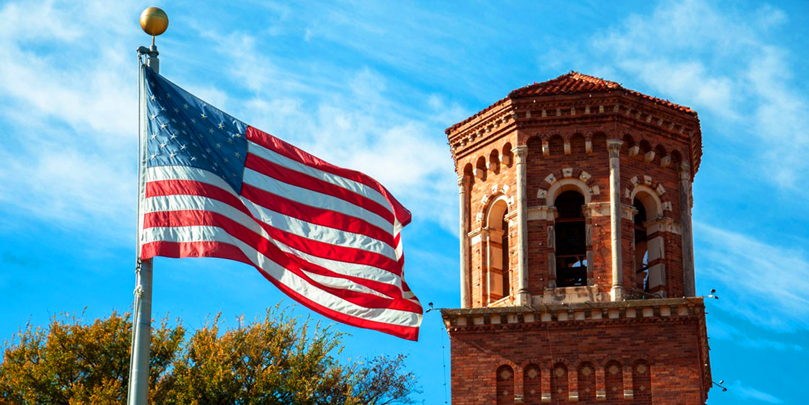 The Hardin Administration building tower with a flag in the foreground