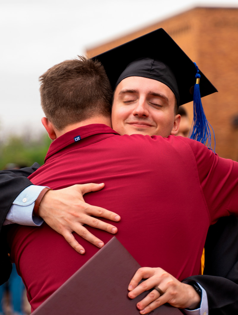 Male MSU grad getting a hug