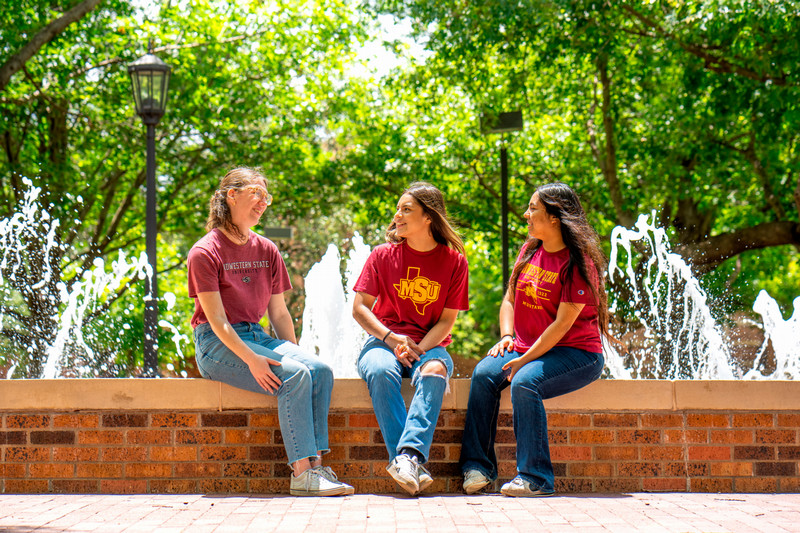 Three students sitting on the Bolin fountain