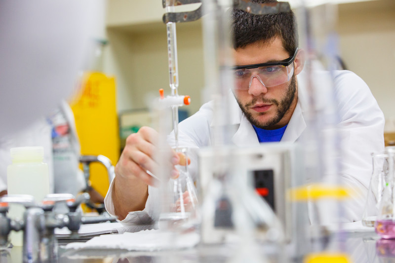 Student in a lab coat with a beaker