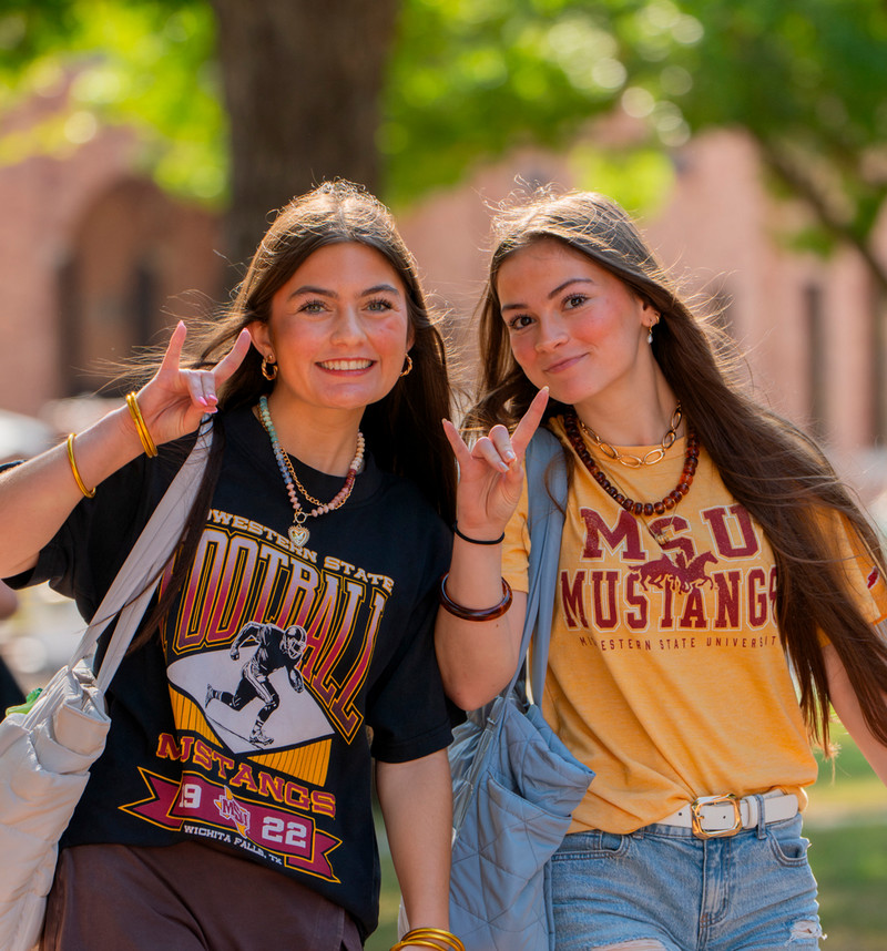 Two young ladies on campus, stangs up